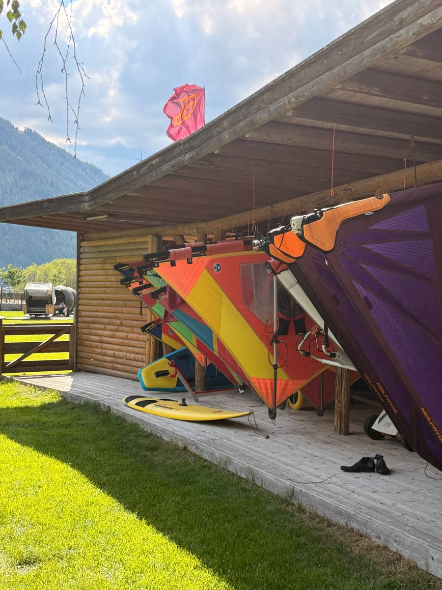 Bunte Windsurfsegel aufgeriggt unter dem Holzdach der Station