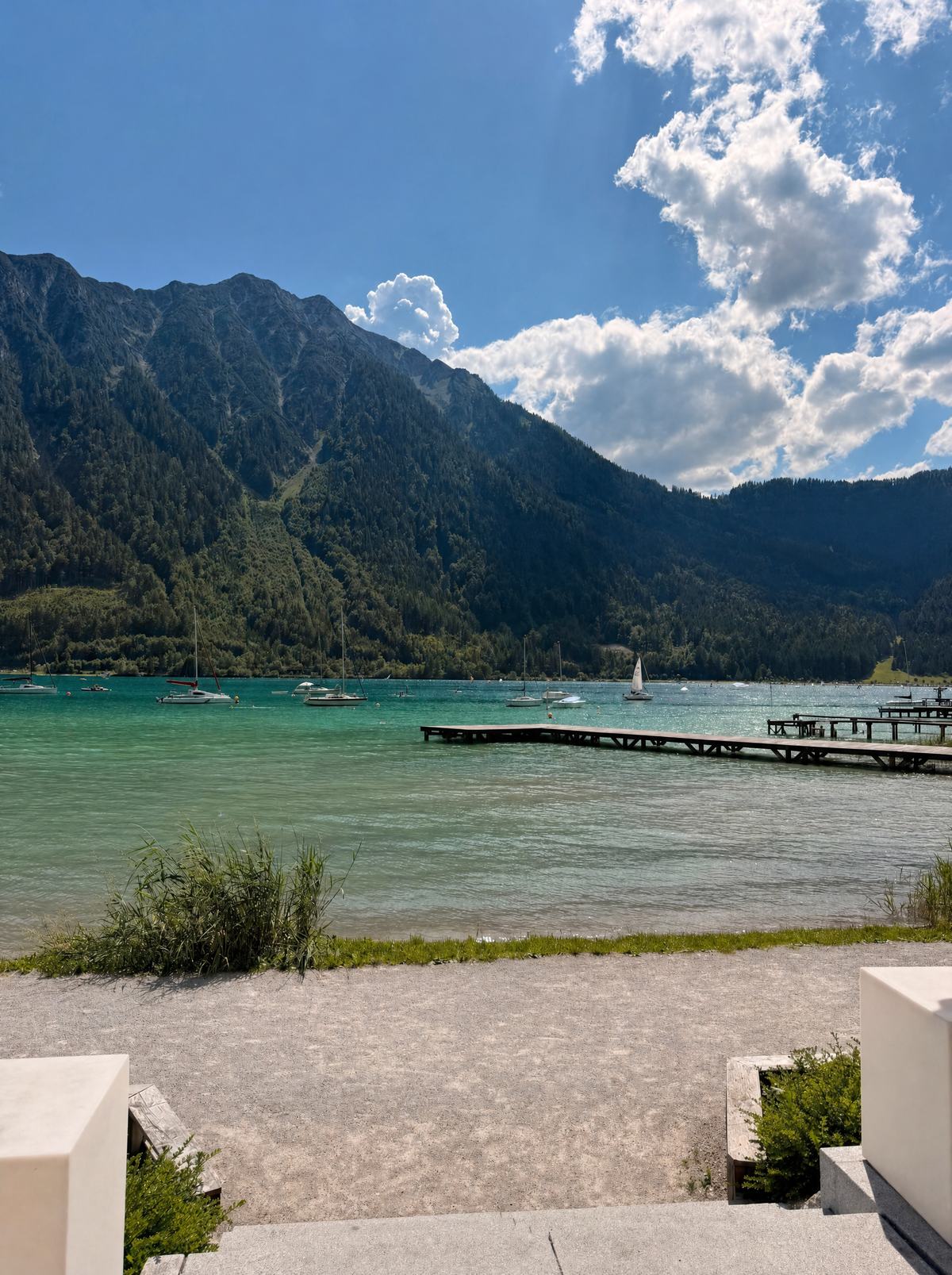 Türkises Wasser des Achensees mit Steg und steilen Bergflanken